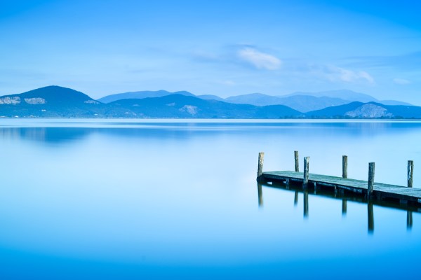 Wooden Pier Or Jetty And On A Blue Lake Sunset And Sky Reflectio